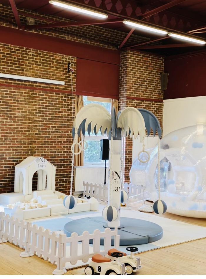 Blue and white first birthday setup in a hall with personalised Carousel Tree, soft play house and Bubble House Dome