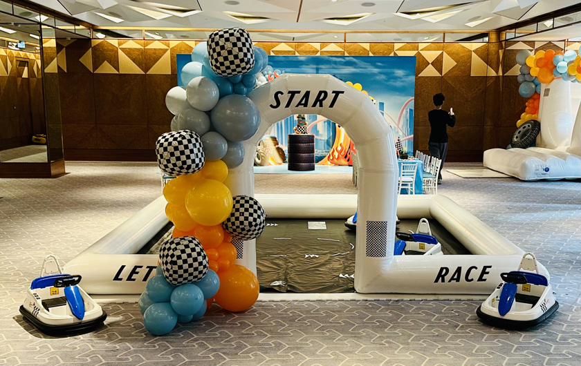 Electric bumper cars around an inflatable Let's Race track with a start arch and balloon garland