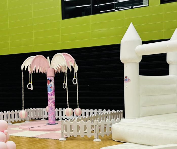 Pink Carousel Tree with themed wrap and white bouncy castle in a sports hall